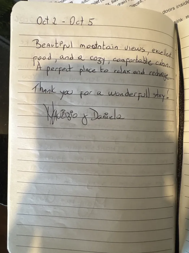 Handwritten guest journal page: Oct 2 - Oct 5 Beautiful mountain views, excellent food, and a cozy, confortable cabin. A perfect pla
